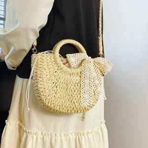 Detail of hand-woven straw bag featuring a white lace bow and round hard handle