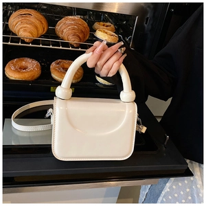 Détail d'un mini sac à main carré blanc crème avec poignée ronde et finition mate