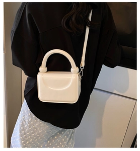 Vue détaillée du sac bandoulière crème structuré avec poignée ronde et accents de boules
