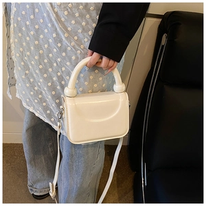 Sac bandoulière crème minimaliste avec anse demi-ronde épaisse porté par un mannequin