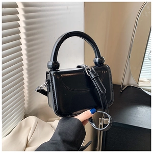 Détail du sac à bandoulière noir brillant avec poignée ronde et finitions argentées