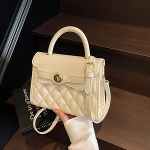 Elegante borsa trapuntata beige con chiusura dorata su scala vintage