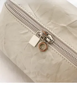 Détails macro d'une fermeture éclair argentée sur un sac plissé blanc crème pour femme