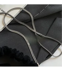 Detail of silver woven metal chain strap with black pleated handle on neutral fabric