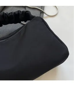 Detail of black nylon pleated shoulder bag showing silk-like texture and metal chain strap
