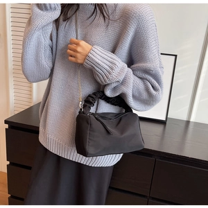 Detail of black nylon crossbody bag with ruched cloud handle and silver chain strap