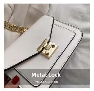 Dettaglio della chiusura dorata e della catena su una borsa a tracolla in pelle beige elegante