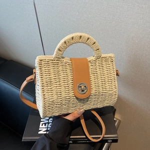 Handwoven straw tote bag with brown leather trim and metal twist lock closure
