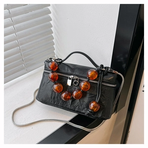 Détail du sac plissé noir avec perles ambrées et bandoulière en chaîne argentée
