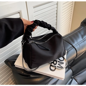 Detail of black nylon handbag showing dual zipper closure and ruched handle design