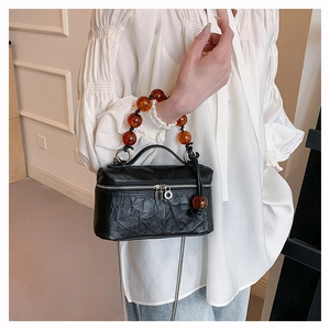 Détail du sac bandoulière plissé noir vintage avec poignée en perles d'ambre et chaîne