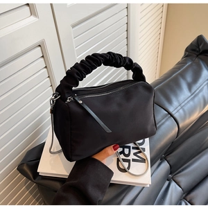 Close-up of black nylon handbag featuring stylish scrunchie handle and silver chain strap
