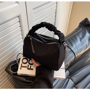 Detail of black nylon dumpling bag featuring ruched cloud handle and silver chain strap