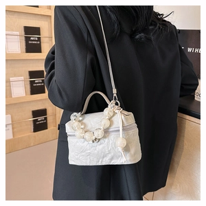 Détails de la poignée perlée et texture plissée du sac bandoulière blanc à chaîne