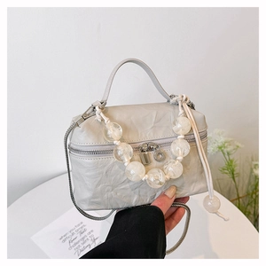 Détail du mini sac plissé gris avec poignée en perles et bandoulière en métal