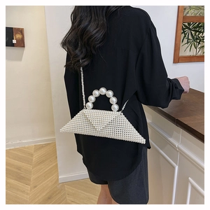 Détail d'un mini sac en perles blanches de forme triangulaire avec longue bandoulière