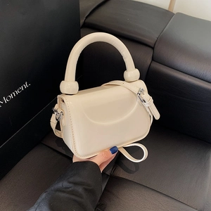 Sac à bandoulière minimaliste blanc crème avec poignée ronde et sangle réglable sur fond noir