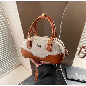 Detail of Boston bag showing beige canvas, brown faux leather trim and PAN TOR logo