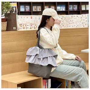 Détail d'un sac cabas en toile grise avec volants violets dans une bibliothèque