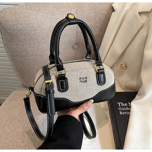 Detailed view of canvas and leather bowling bag with gold hardware on a casual sofa