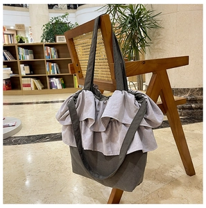 Détail du sac cabas en toile grise avec volants superposés et bretelles contrastées