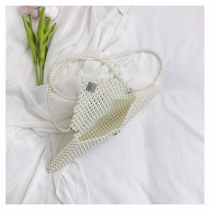 Détail d'un sac enveloppe en perles blanches avec fermoir magnétique et décor de tulipe