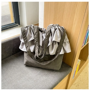 Détail du bord à volants et de la texture en toile grise de ce grand sac seau moderne