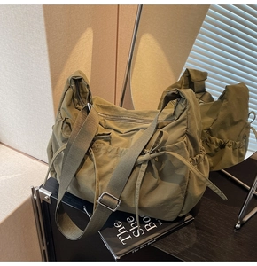 Detailed view of olive green nylon tote with decorative side ribbon and adjustable strap
