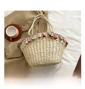Detail of bohemian woven straw tote with colorful tassel fringe and round top handle