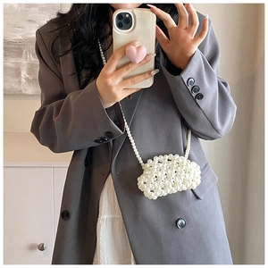Detailed view of cloud-shaped pearl beaded mini bag worn with a casual gray suit