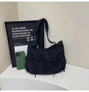 Detail of black nylon crossbody bag featuring stylish bow ribbons and drawstring side pockets