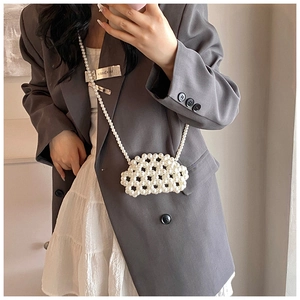 Mid-shot of a cream handmade woven pearl cloud mini bag with beaded crossbody strap