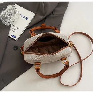 Detailed top view of a cream bowling bag showing brown leather trim and golden zipper