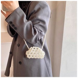 Detailed view of a white pearl beaded mini bag worn as a crossbody accessory