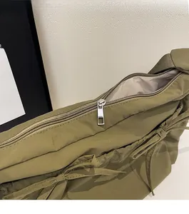 Close-up of olive green nylon bag featuring a smooth silver metal zipper and beige lining