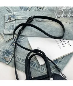Detail showing the adjustable thin leather shoulder strap and silver metal buckle of black bag