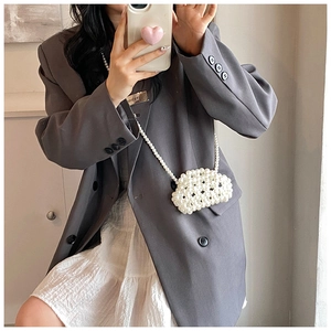 Mirror selfie showing a woman wearing a handmade white pearl woven mini crossbody handbag
