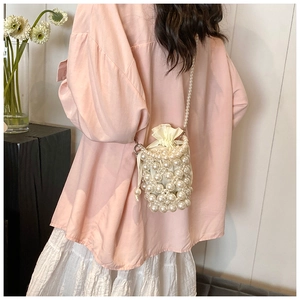 Détail du sac seau en perles blanches avec fermeture à cordon et bandoulière