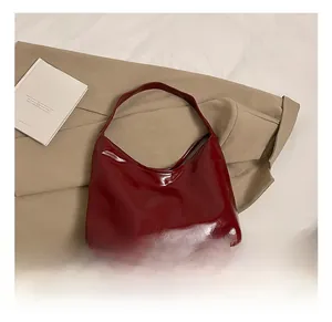 Close-up of glossy burgundy faux leather shoulder bag with sleek minimalist texture