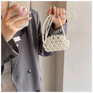 Detail of handcrafted cream pearl mini handbag with bead chain strap for elegant styling