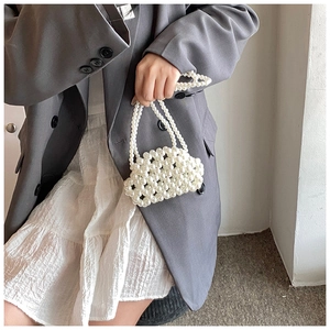 Detailed view of a handmade white pearl beaded mini handbag with an elegant top handle