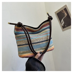 Détail du sac seau bohème en paille colorée avec anses en cuir et accents métalliques