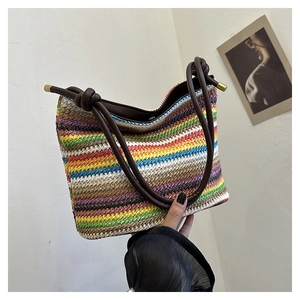 Détail du sac seau en paille tressée colorée avec poignée en cuir marron et nœud chic