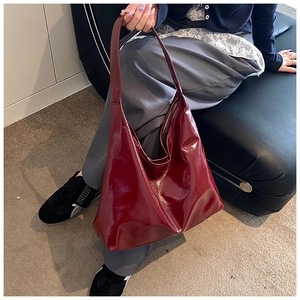 Detail of burgundy hobo bag in glossy patent leather finish with spacious design