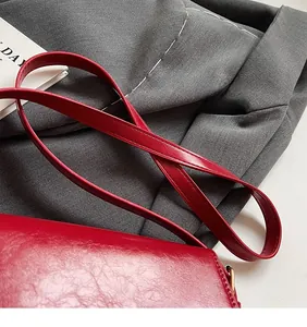 Gros plan de la longue bandoulière réglable sur un sac à bandoulière en cuir rouge vintage