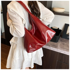 Large bright red hobo shoulder bag shown on model with smooth glossy leather finish
