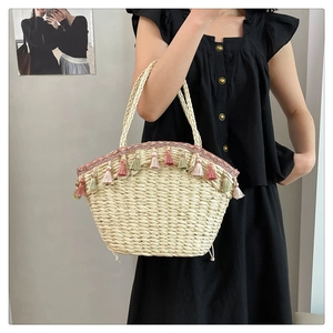 Detail of hand-woven straw bag featuring colorful tassels and ethnic pattern ribbon