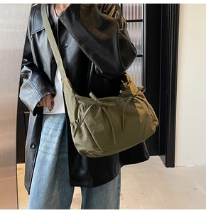 Detail of olive green nylon crossbody bag with bow knots and adjustable strap