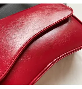 Détail de la texture cuir rouge cerise brillant et logo doré imprimé sur le sac