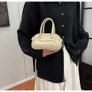 Detail of off-white grain leather handbag with puffy curved design and shoulder strap